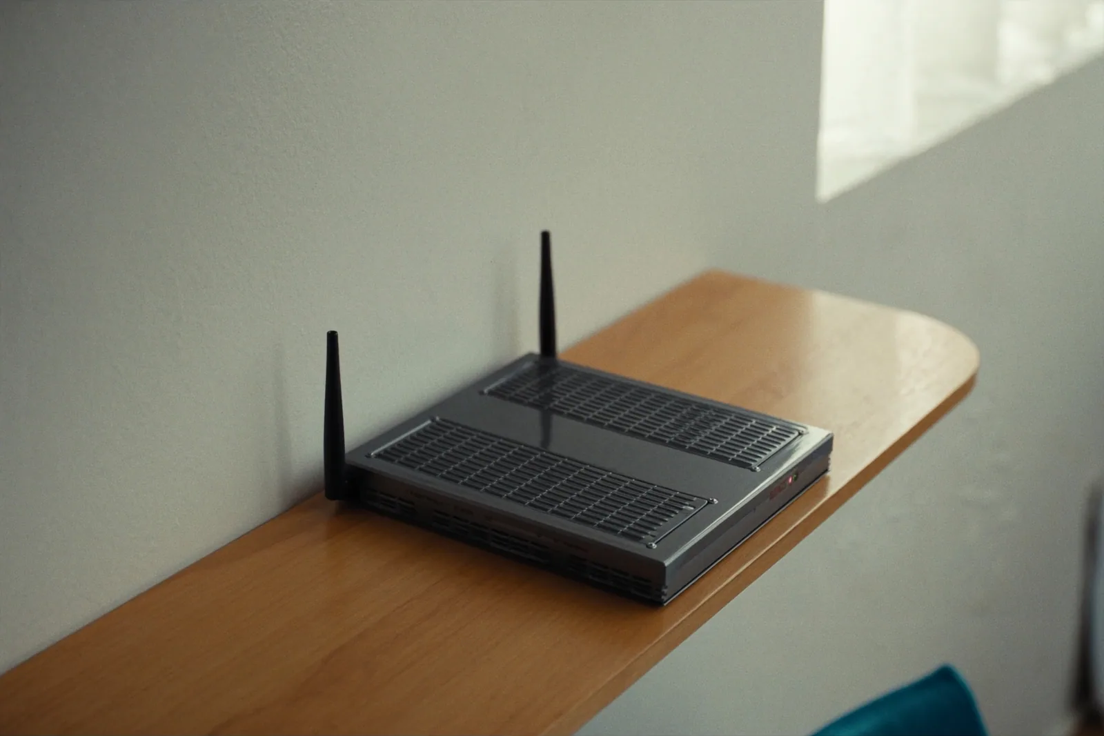 A compact 4G router with two antennas on a timber shelf in a small office